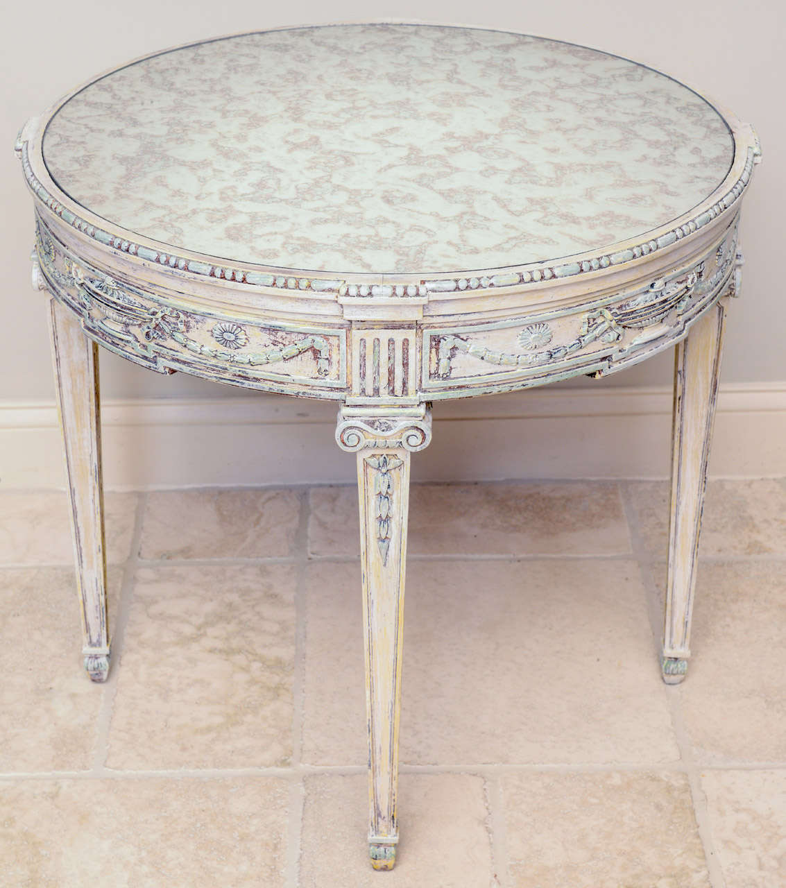 Round accent table, having a distressed painted finish, spotted mirrored top inset in apron carved with beading, urn, swag and rosette motifs, raised on square tapering legs with laurel leaf details.

Stock ID: D6608