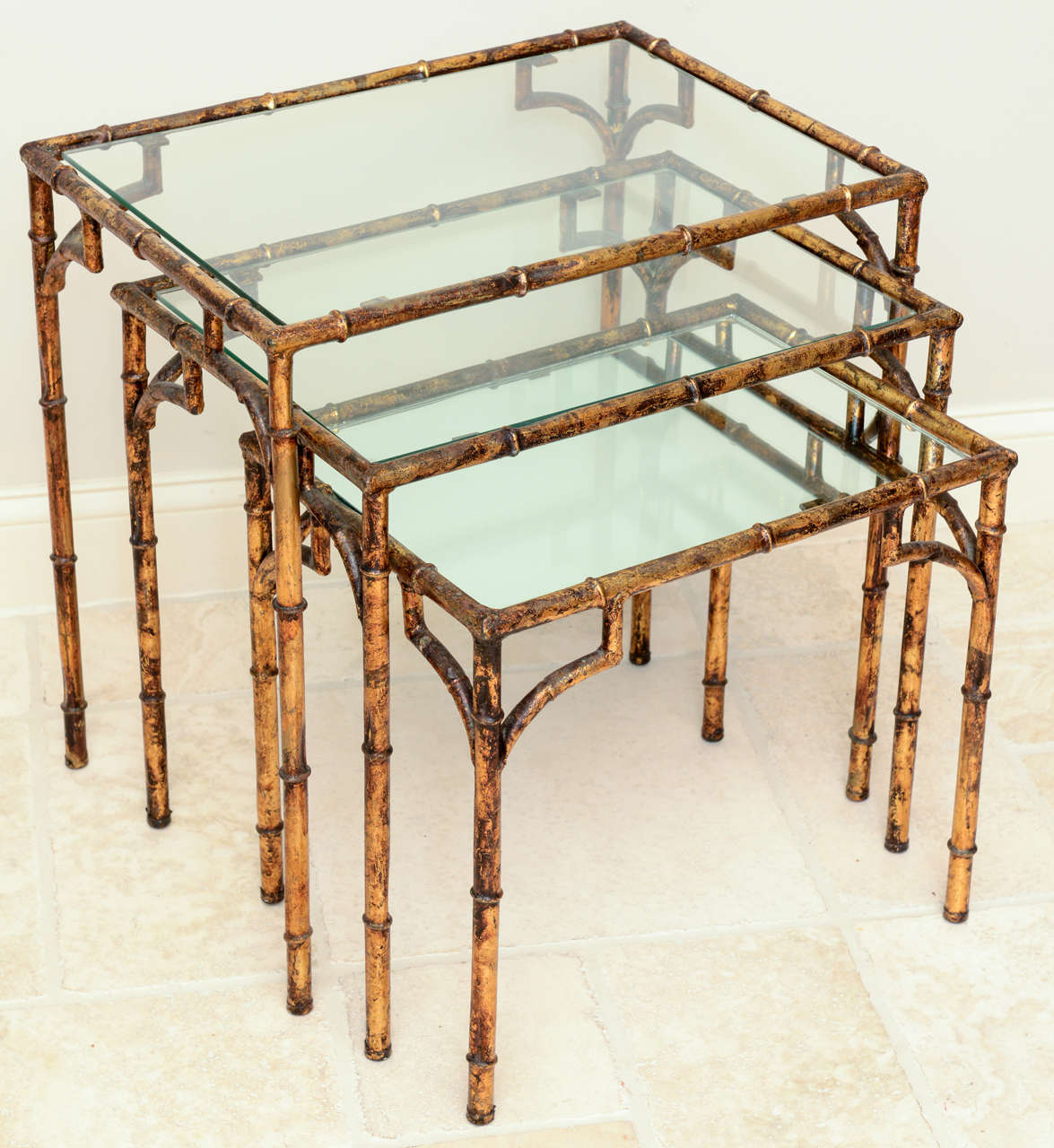 Set of three faux bamboo nesting tables, of gilded iron, having glass tops on the two largest and a mirrored top on the smallest.  (Smallest measures 16 1/2