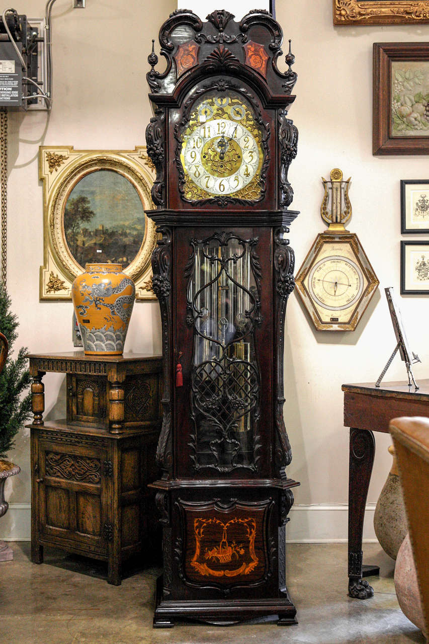 English nine tubular bell quarter chiming hall clock by Elliott in ornate carved and inlaid mahogany case with a heavily engraved brass dial accented with silvered chapter rings, a seconds dial and ornate blued hands. The clock features both