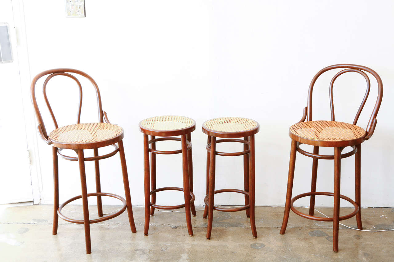 An assortment of four Thonet barstools with classic bentwood frame and caned seats. Group together for a fun mix or will split into two pairs. (backless stool 12.5