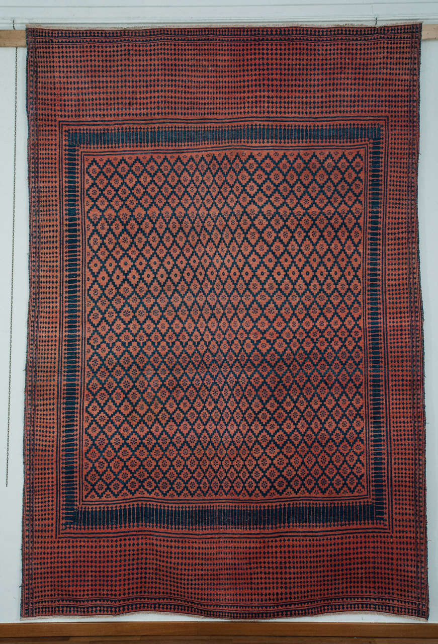 An unusual cotton flatweave, quite possibily related to the Indian Dhurrie tradition, decorated by an honeycomb arrangement of light blue lozenges on a salmon rose background. The restricted palette derived from madder and indigo plants creates a