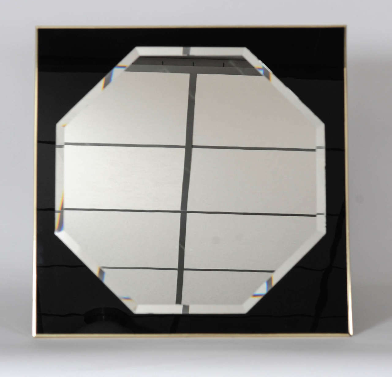 Heavy quality mirror in 1980s nightclub style.
This octagonally shaped mirror (52 x 52 cm) is attached to a black glass square framed by a brass strip.