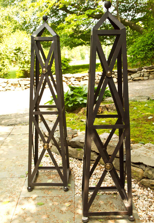 Pair of wrought iron regency style x-form obelisks with bronze roundel decoration raised on ball feet