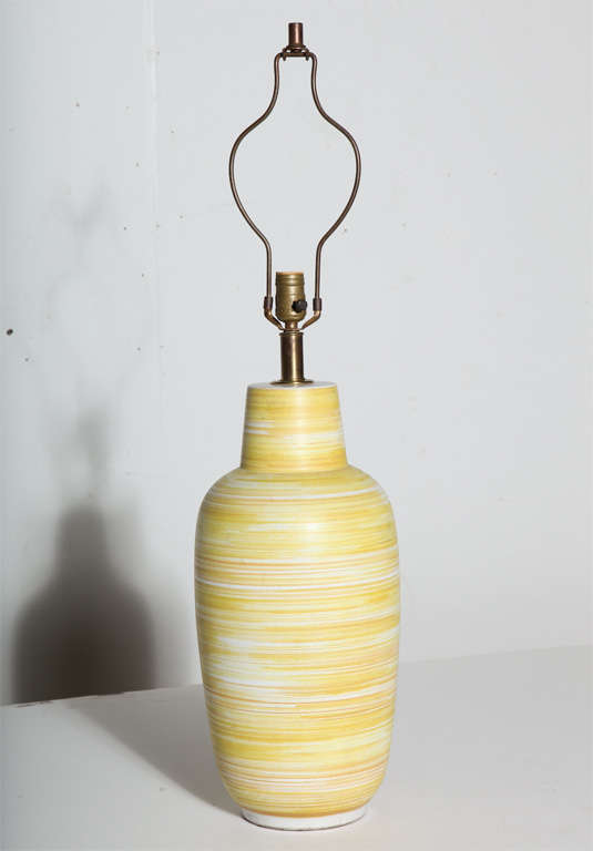 Tall Design-Technics handcrafted glazed striated yellow and white matte ceramic table lamp. Featuring the Design Technics classic bottle form with horizontal banded swirl design in vibrant bright yellow and thin orange detail against white. Brass