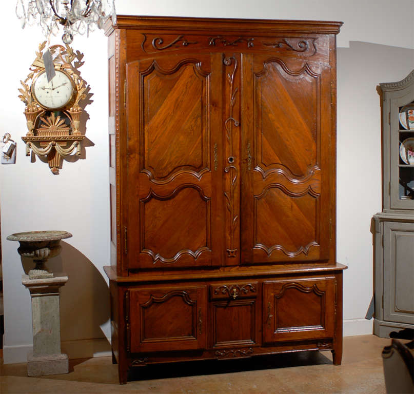 A French Louis XV style carved oak buffet à deux-corps from the Eastern part of France, early 19th century. This French oak two-part cupboard features a tall upper cabinet, adorned with a molded cornice sitting above a floral-carved rail. A set of