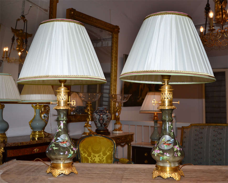 Pair of table lamps with decor of coloured birds on a grey back ground, on gilded bronze base.
That pair of petroleum lamps is newly electrified - the lampshade is hend made in wrinkled silk
