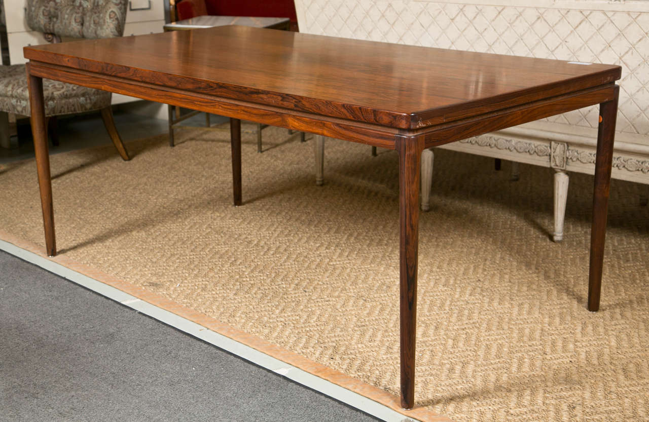 A mid-century modern Danish rosewood dining table, approximately from 1970s, of streamlined form, rectangular top with pull out support with an extra leaf on each side (20