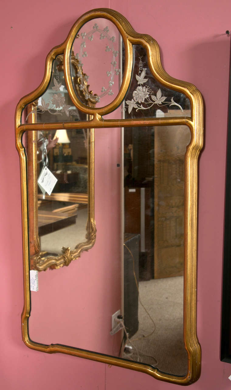 A lovely giltwood mirror in the Hollywood Regency style, the top part with etched glass depicting floral and clover pattern, over a rectangular plate, all surmounted in giltwood border.