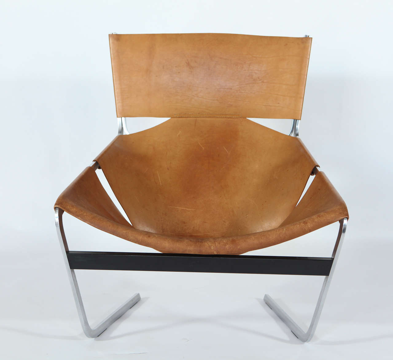 Leather lounge chair by Pierre Paulin, model F444. Naturally patinated saddle leather. Chrome-plated and enamel steel frame, linking black rail between legs. 

Designed by Paulin for Artifort in 1963.  

Signed with applied metal label.  
