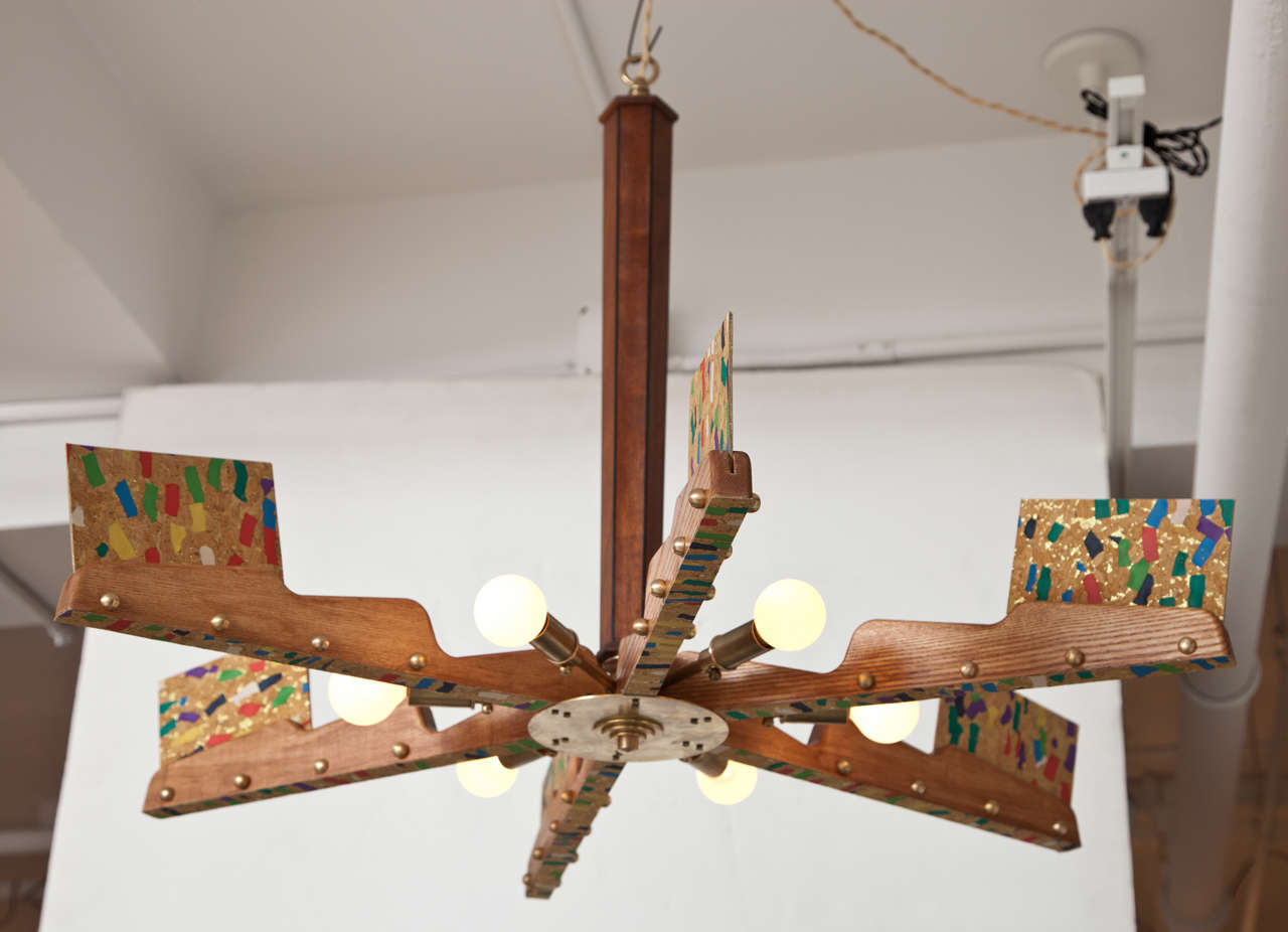 Whimsical six-arm chandelier.  Germany, circa 1980.  Made of wood with brass accents and multicolor mica decoration.

Wired for U.S. Takes six candelabra bulbs, 60 watts max.