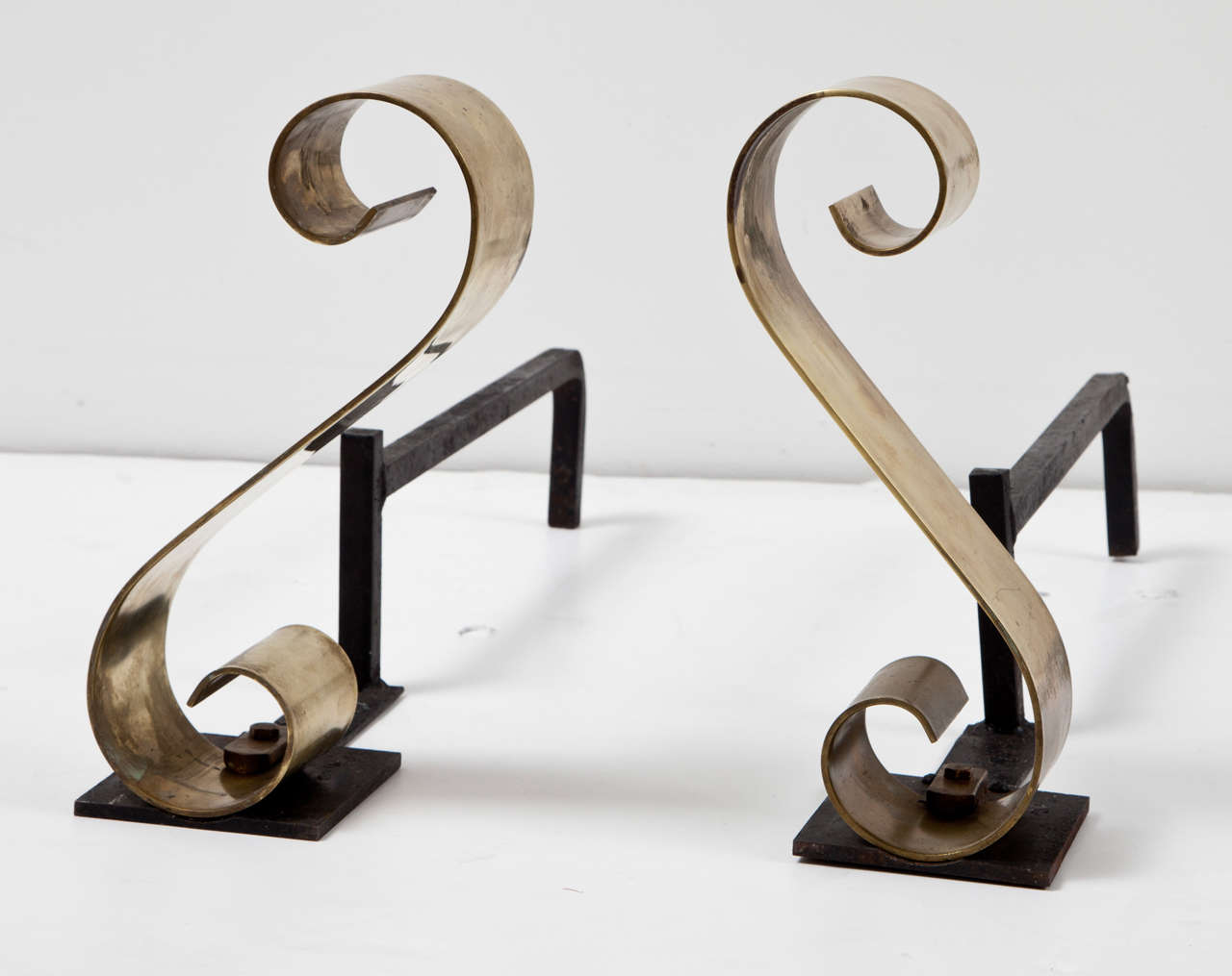 Scroll-design andirons in polished brass with black iron log holder.  USA, circa 1950.  Brass features original patina.
