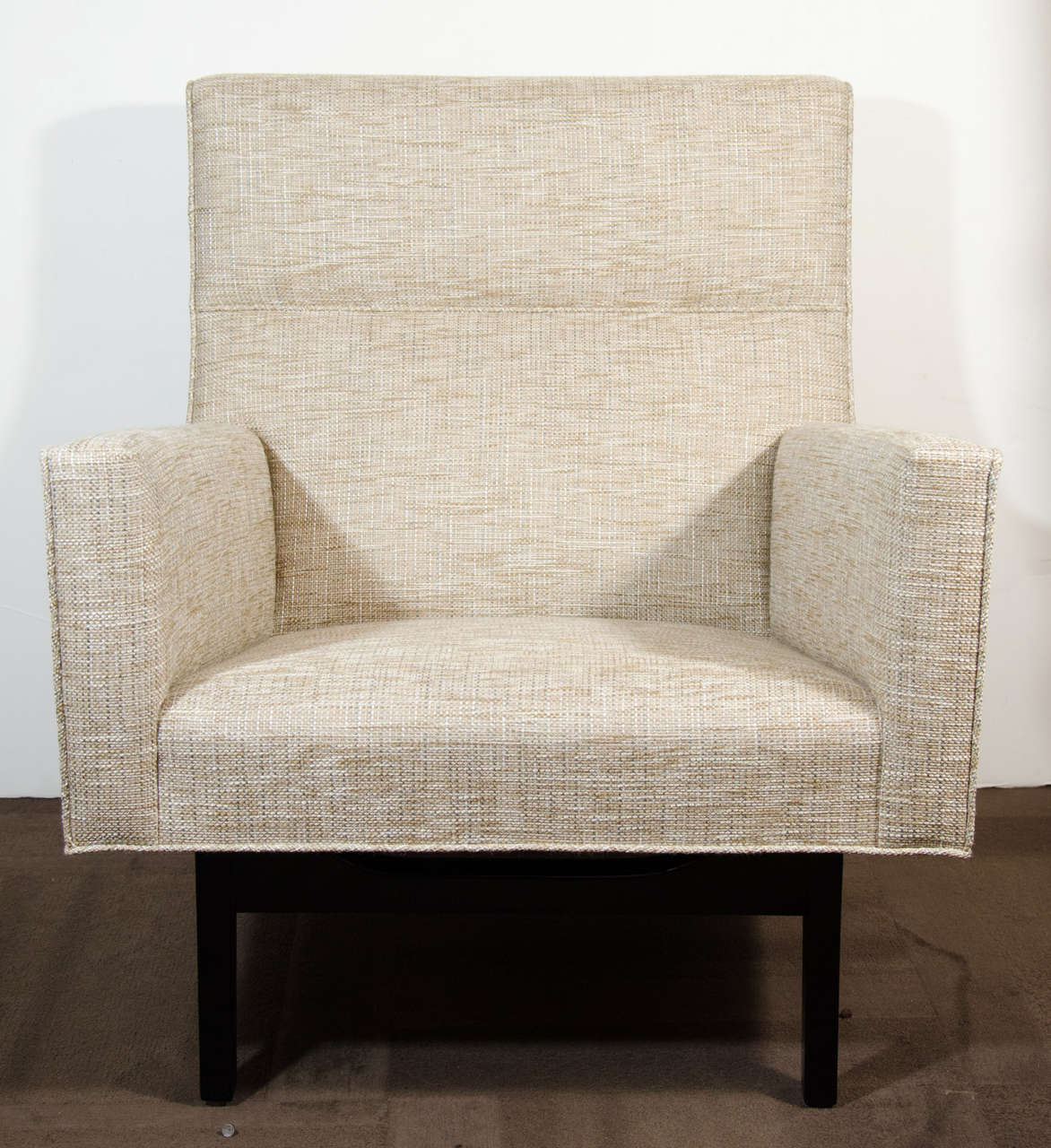 Outstanding modernist lounge chair with sculptural design.  The chair features highly angled lines as well as a striking base and leg design in walnut wood with an ebony finish. Newly upholstered in a fine woven tweed fabric in hues of ecru, ivory,