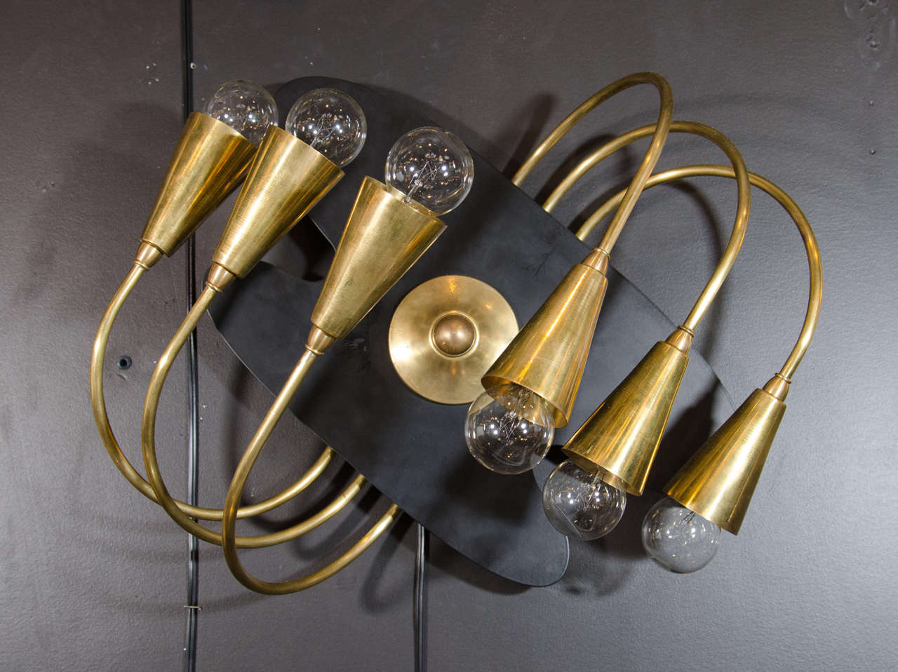 Spectacular pair of rare sculptural brass sconces. The lights feature a six arm modern asymmetrical scrolled design with an amorphous shaped wall-mounted backplate in a black enameled metal. Highly stylized form that also function as wall sculptures.