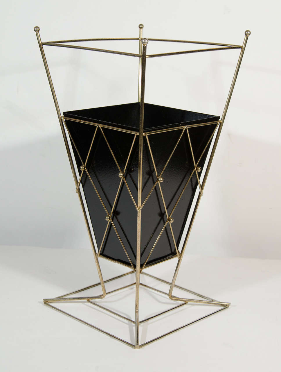 Mid century umbrella stand with stylized caged frame with geometric form in patinated brass, and with black enameled tin center.