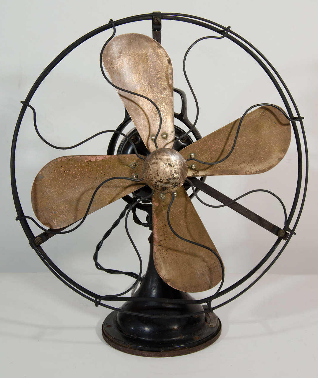 Art Deco era electric table fan with modern industrial design. Fan has heavy steel base and iron cage frame in a black enameled finish, with blades of copper metal. Fan has swinging head design and is in great working condition with three adjustable