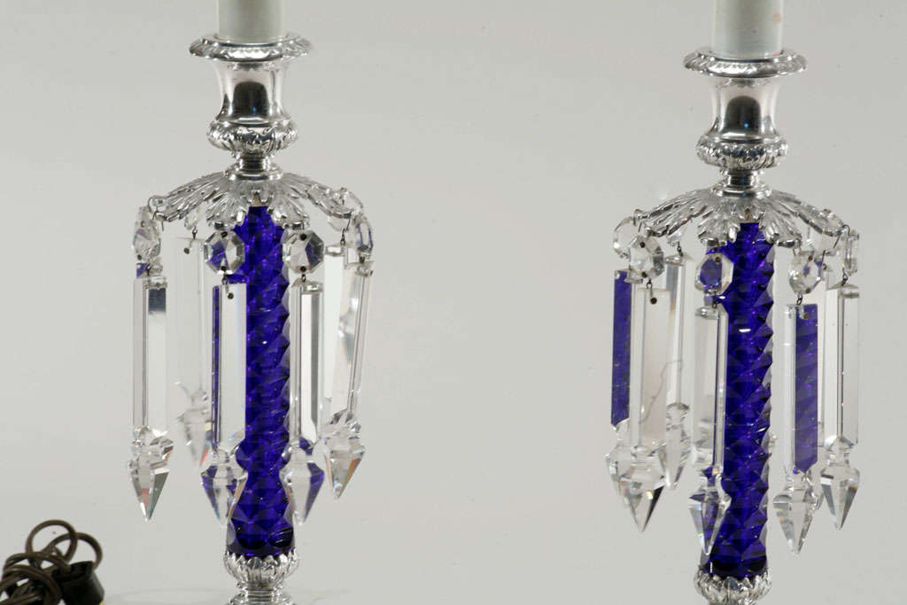 This a rare pair of silver plate mantel or table lamps with all original fittings. The standards are honeycomb cutting of the finest cobalt blue crystal. The leaf shaped bobeches hold matching prisms, all in fabulous condition. These are signed
