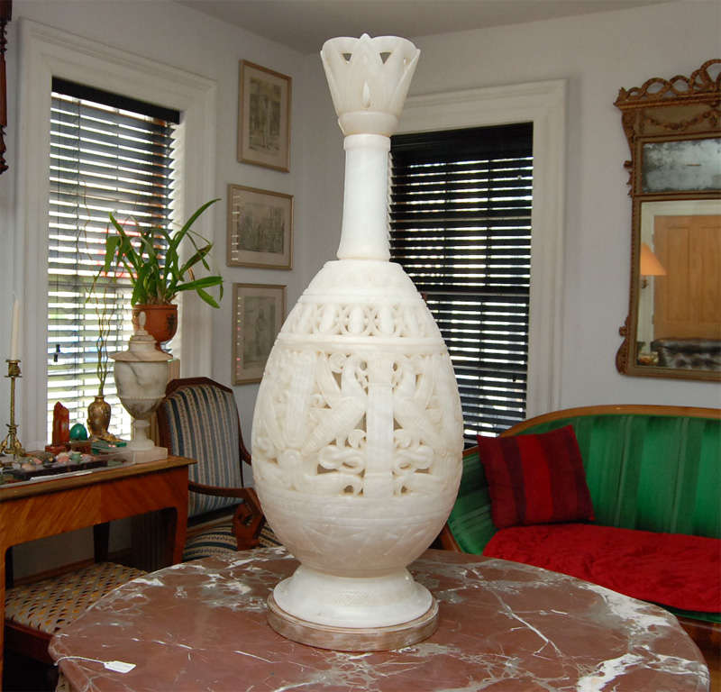 Executed in an ancient style this vase once made into a lamp has many Egyptian elements. They include stylized vultures, scarabs, papyrus, lotus columns, and water lilies. The large body is carved from a single translucent piece of alabaster and is