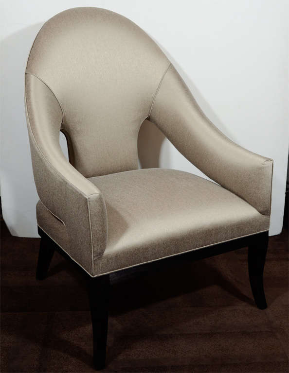 Pair of elegant and modern arm chairs with
stylized cut-out backs and curved spoon 
back design.  Chairs have saber form legs
in ebonized walnut and have been newly
upholstered in metallic taupe sharkskin.