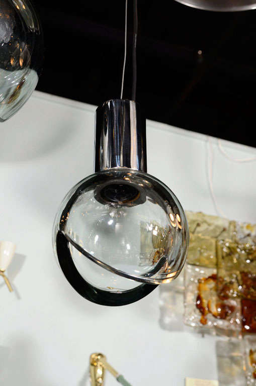 Un globe en verre gris soufflé à la main des années 1960 et une suspension chromée produite par la célèbre maison de verre Seguso à Murano, en Italie. Il présente une découpe en forme de tarte sur le fond et est suspendu à un raccord en laiton