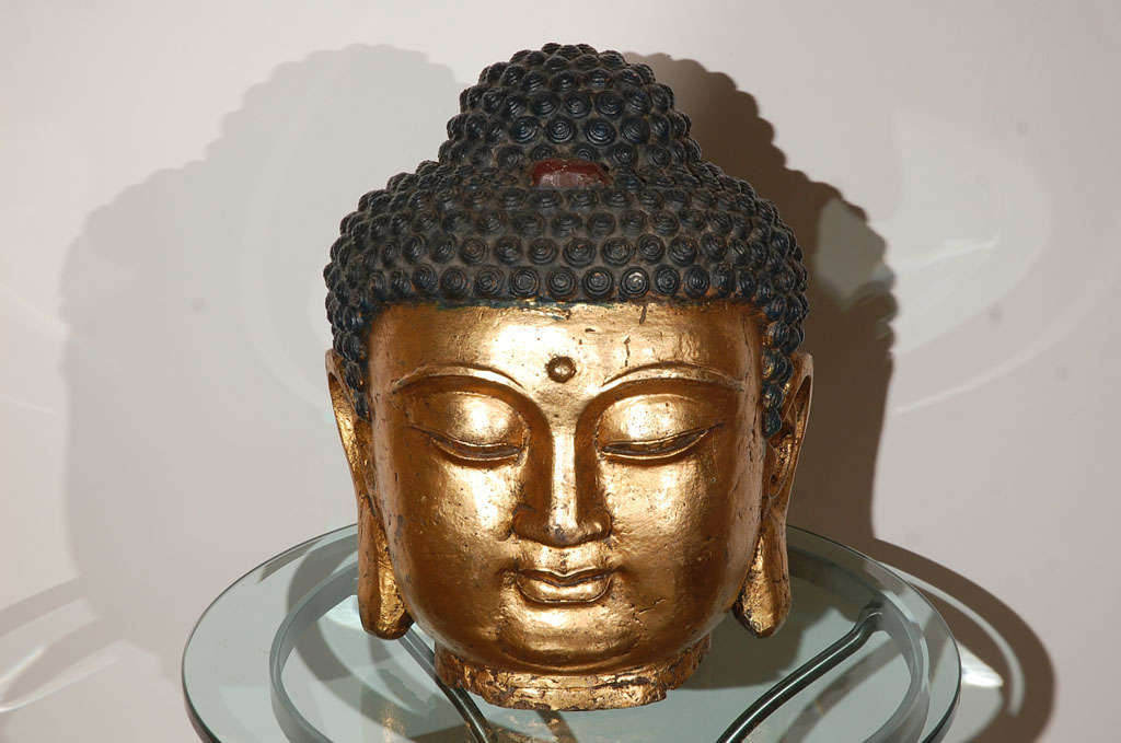 A Tibetan Gilt Bronze Buddha Head 
17th/18th Century
From what originally would have been a life-size statue, this Head is crafted in the repousse technique and features a rich overall gilding. 

Mosaik Specializes in rare 18th, 19th century