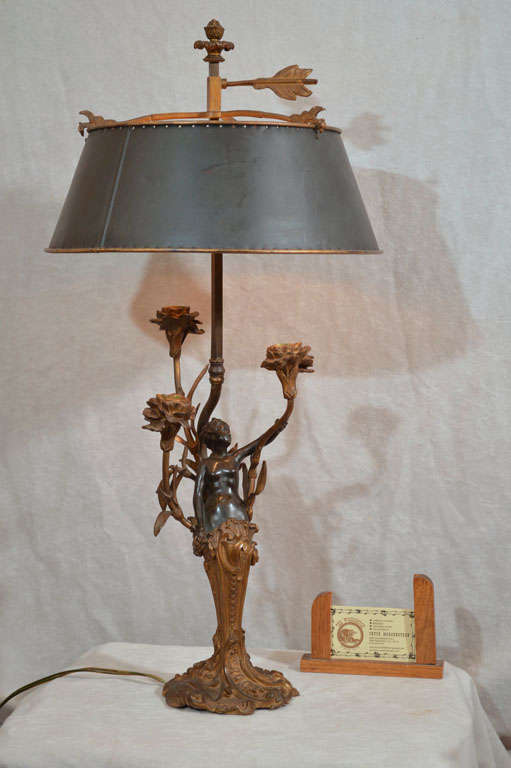 This very unusual example of the Art Nouveau period has a beautiful two-color patina and the original metal shade. It's quite rare to find the original shades to lamps such as this. The shade has little pierced circles to let the light pass through.