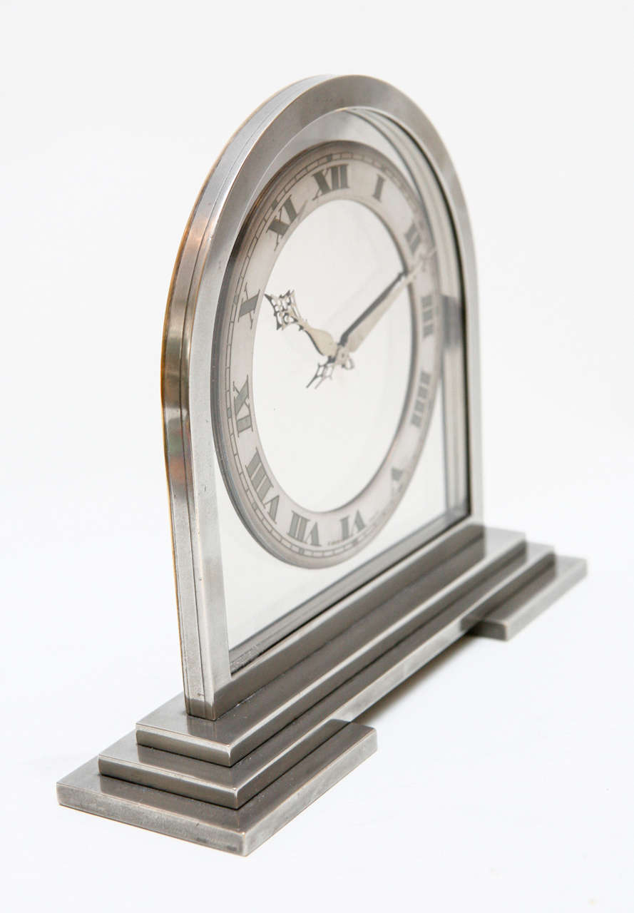 This burnished nickel Art Deco clock looks like it could have come straight out of The Great Gatsby. The clock has a mirrored face with a raised incised metal dial and features an 8-day Swiss movement. Stamped on the back 