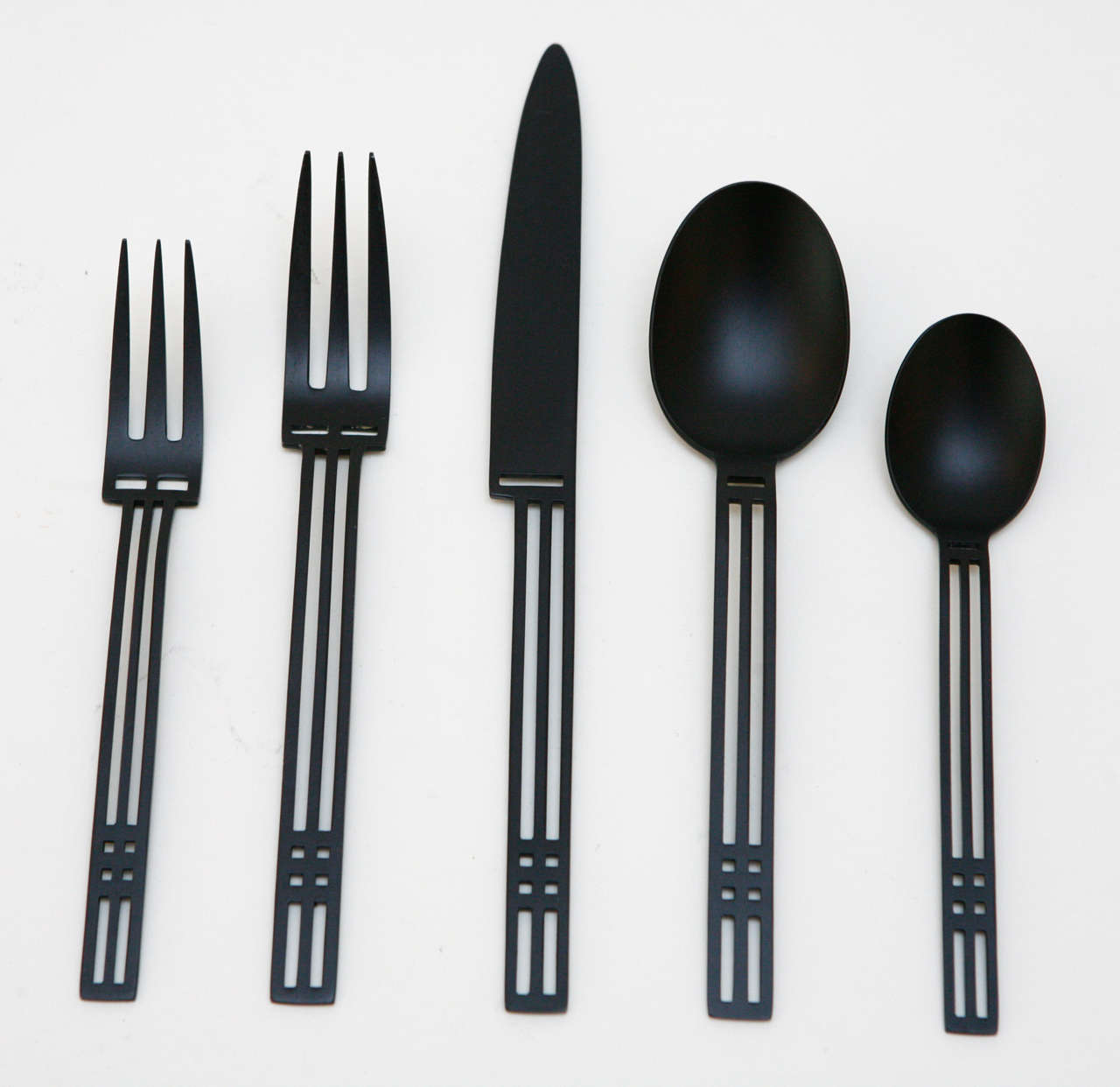 A striking modernist flatware service for twelve by Patino/Wolf for Sasaki in the anodized black stainless steel finish of their 