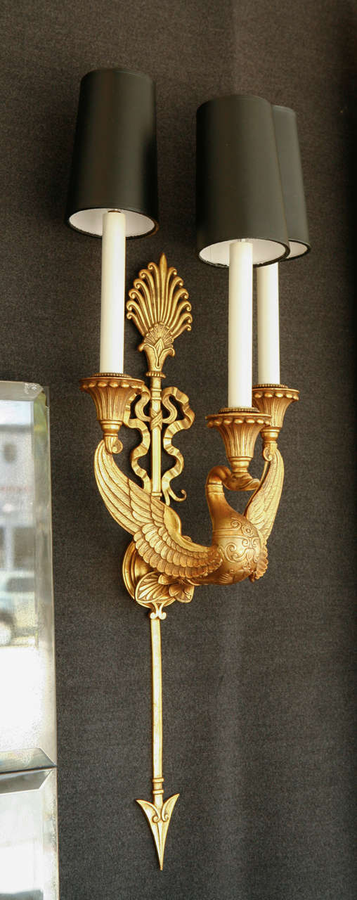 A winsome pair of three-arm Napoleonic style candlestick bronze sconces featuring swans, an arrow, ribboning and a fan detail. They've been newly rewired and have custom black paper shades. Stamped 