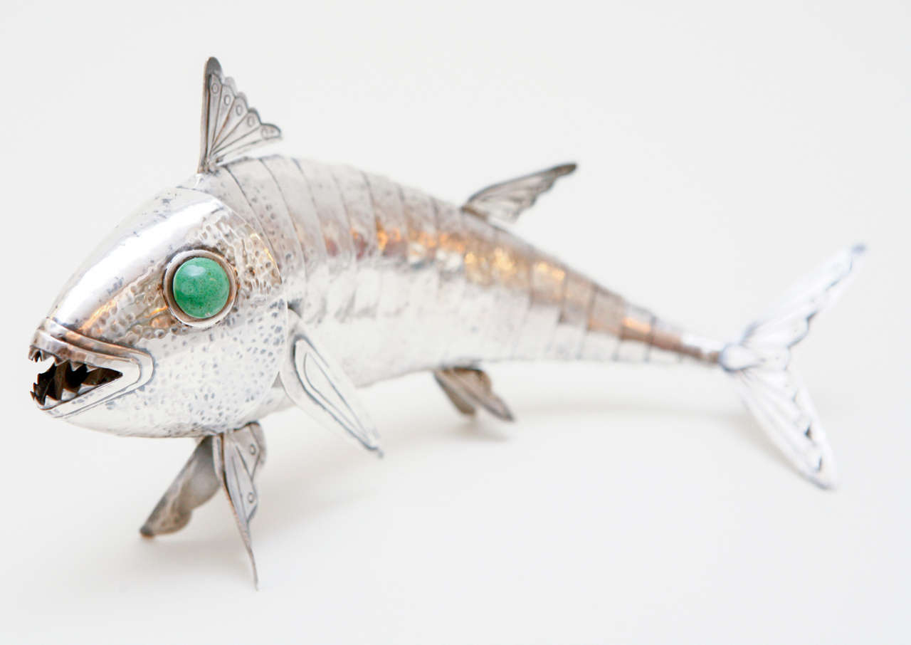 An articulated sterling silver fish with green glazed ceramic eyes. Stamped on the tail 