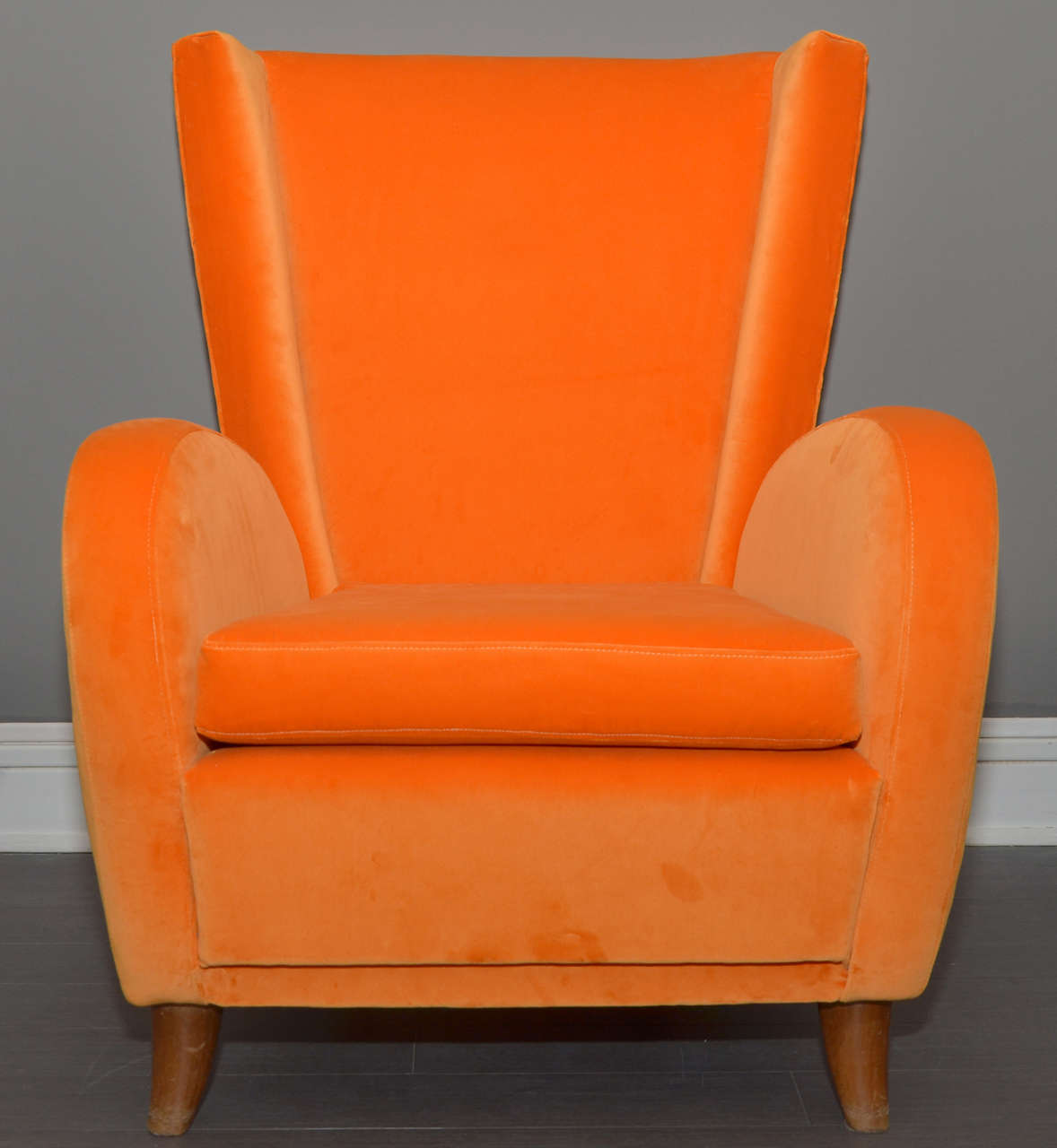 Two 1950s Italian armchairs, reupholstered in orange velvet, with wooden legs.