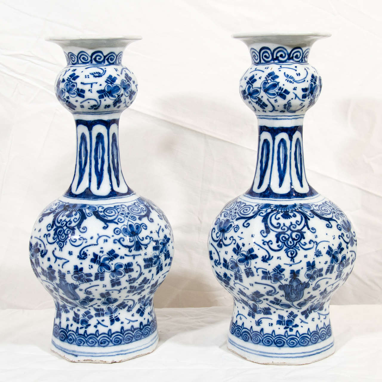 Provenance: From the collection of Katherine Mellon
A pair of Dutch Delft Blue and White vases with an all over design of tulips and other flowers. At the top and bottom of the vases are bands of scrolling. On the shoulder of each vase are