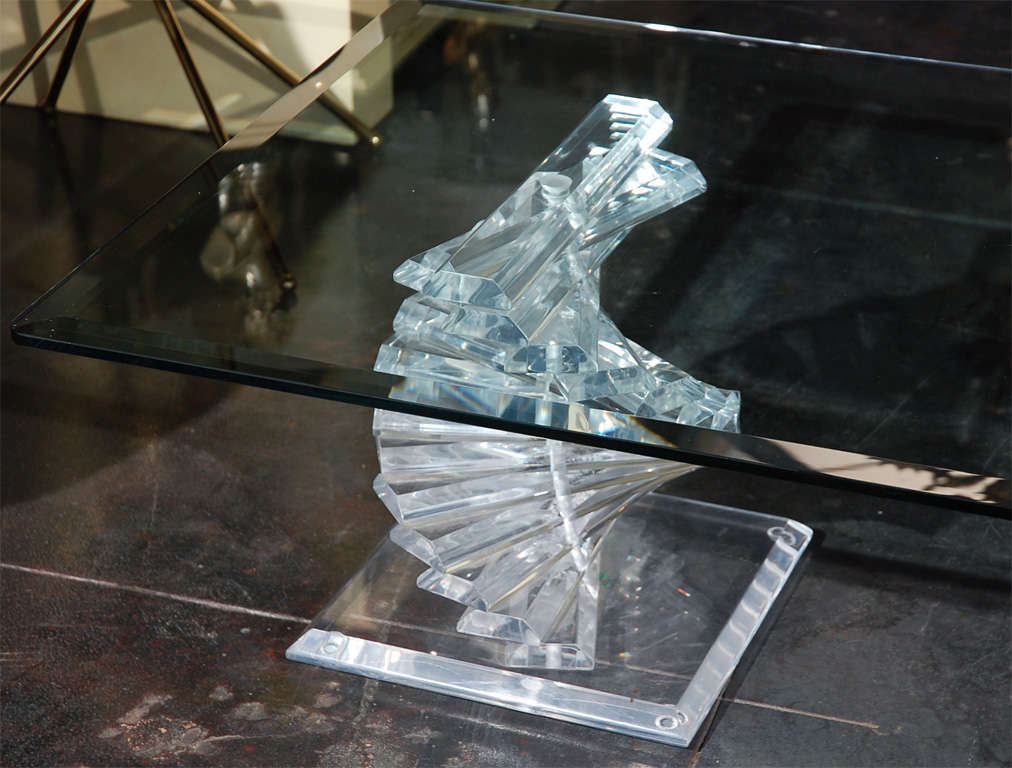 A swirling Lucite coffee table. Made of thick Lucite strips mounted on two beveled Lucite bases. Glass top. See separate listing for a companion side table. Glass top has a 1 1/4