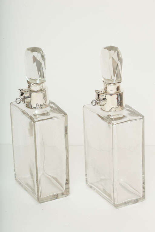 Impressive and rare pair of locking decanters by renowned silversmiths Hukin & Heath. Large in size and scale, these Art Deco decanters feature sterling silver mounts with locks (and keys) and faceted crystal stoppers. They are hallmarked