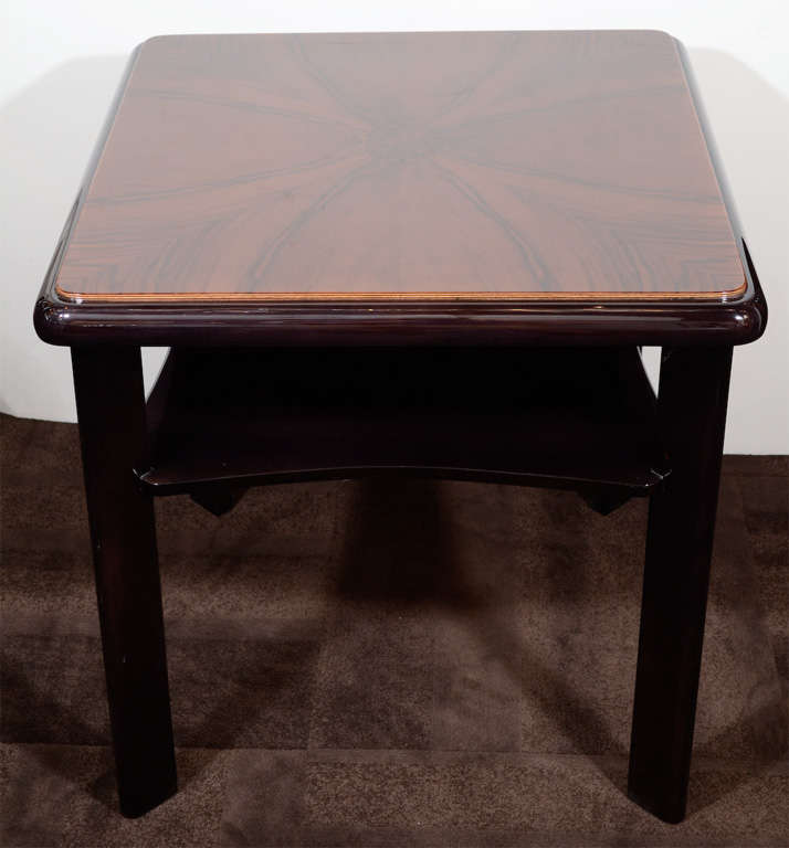 Art Deco occasional table with two tier design in fine bookmatched walnut wood that offers a uniquely stunning grain and with a sable brown ebonized mahogany base. The table has a streamline design on top tier and legs, and a subtle scalloped design