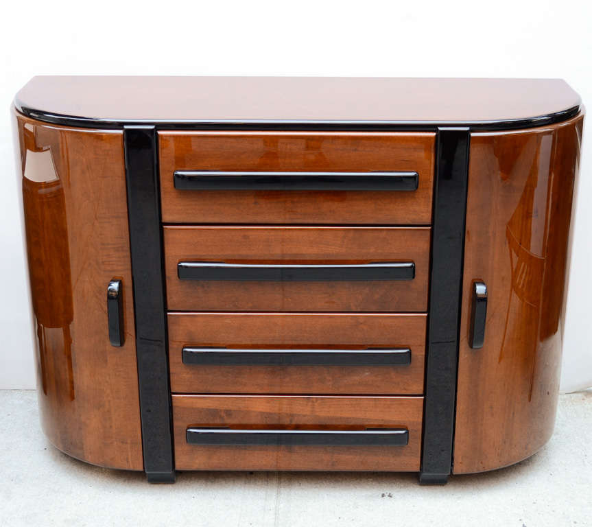 Art Deco cabinet and sideboard with streamline
design in walnut wood with black lacquered details. 
The sideboard has curved front design.  Two outer
doors open to reveal cabinet space with fitted shelves.
The sideboard also has four center
