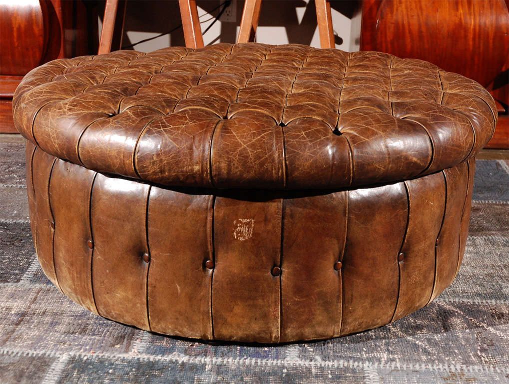 A large round ottoman in tufted leather with beautiful patina