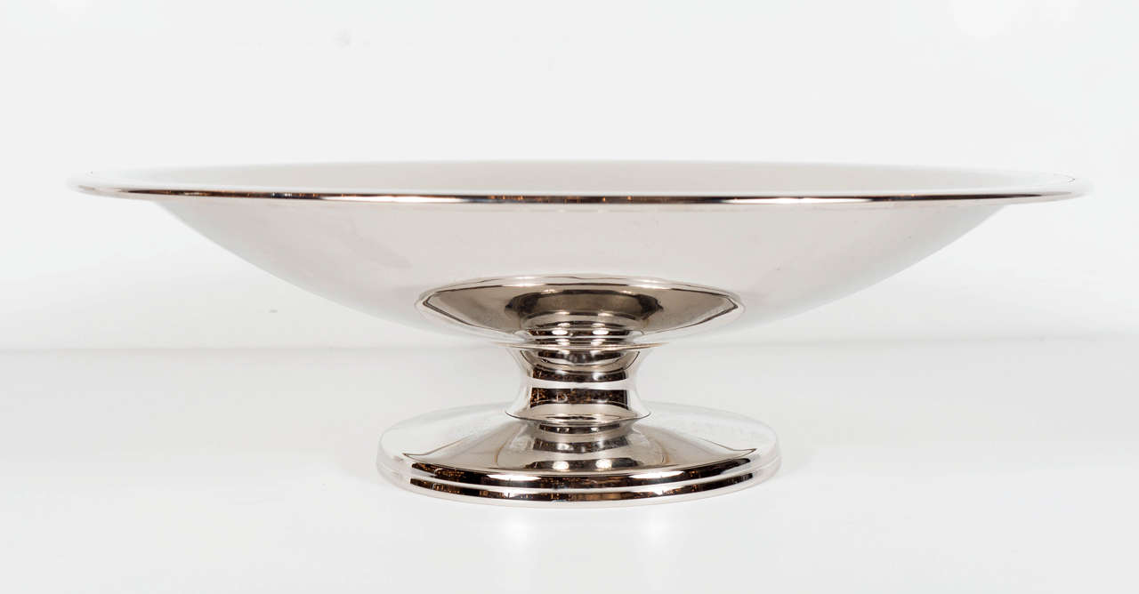 Mid-Century Modernist streamlined footed silver plate bowl designed by Tommi Parzinger for Dorlyn Silversmiths. This exquisite shallow designed bowl sits atop a circular footed base with stepped detailing. The bowl itself features a geometric