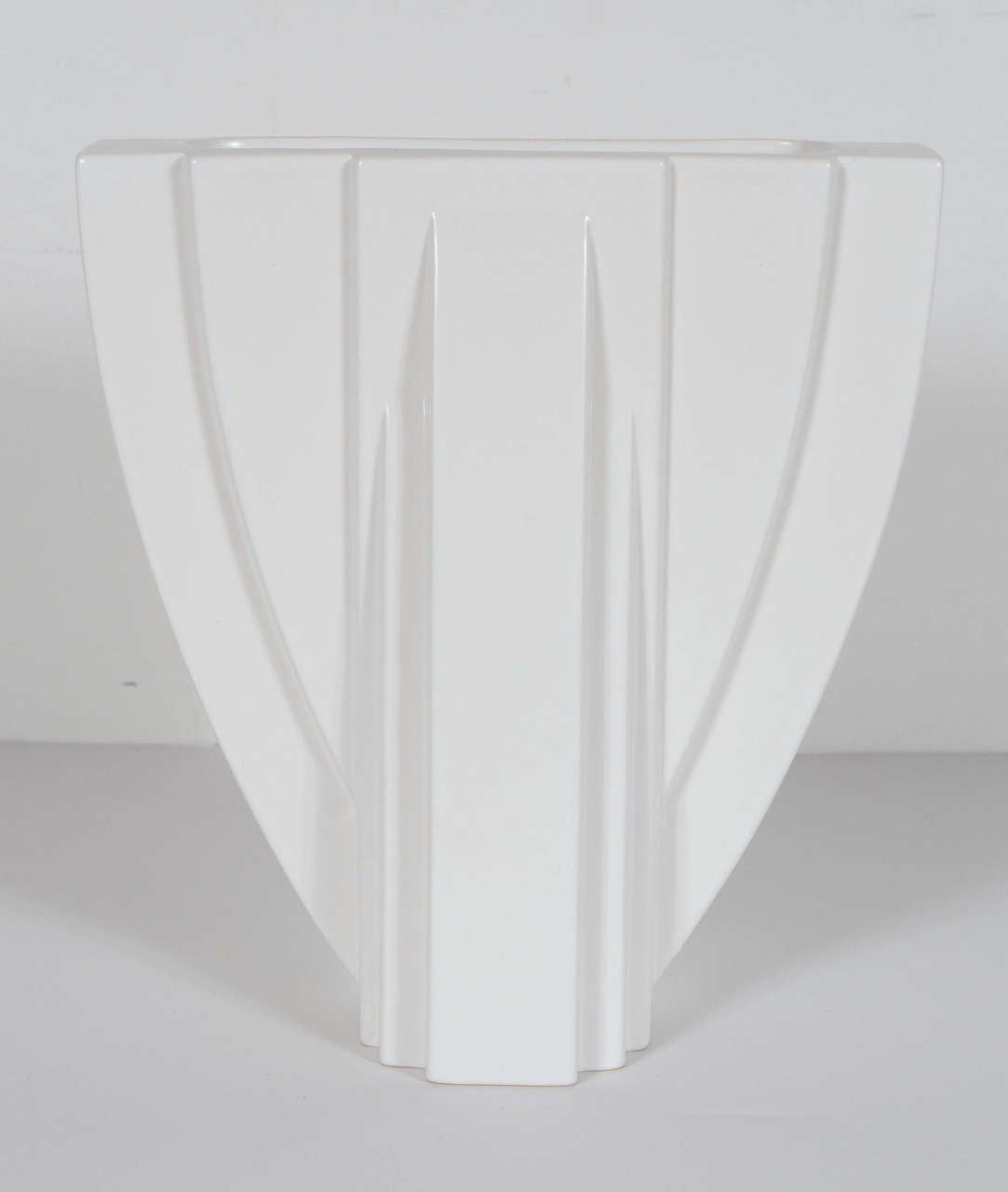 This vase features a reverse arch form with flattened sides molded with geometric and curved extensions in relief, matte crème glaze, raised maker's marks on base. Great skyscraper design very exemplary of the Art Deco period. This vase is in mint