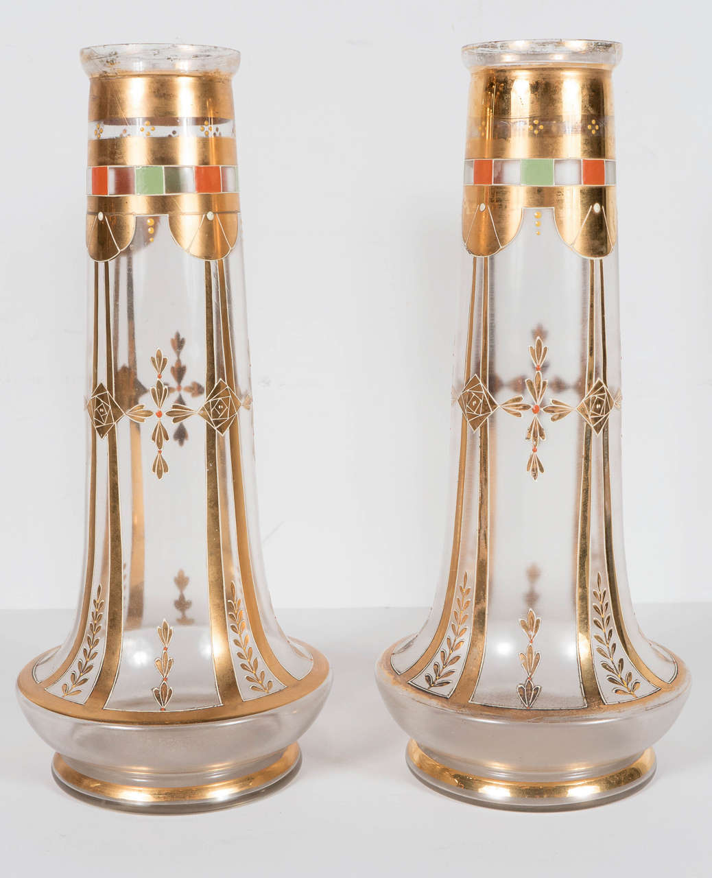 These gorgeous vases feature an elongated 1920s style design with 24-karat gilded embellishments, as well as geometric and floral motifs. There is also some colored enamel detailing, in shades of coral and celadon, under the lip of the vase as well