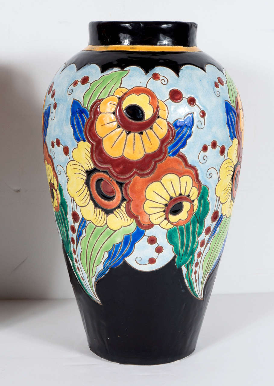 This beautiful pair of Art Deco hand-painted ceramic vases are by Kermis. They feature a lovely stylized Art Deco design foliage and florals, with intricate detailing and an array of vivid colors. These are in excellent condition and are incredible