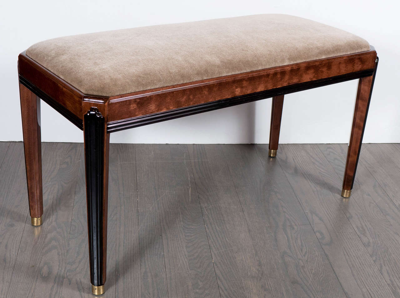 This impressive bench features a stepped skyscraper design in black lacquer on the walnut legs, the legs are also fitted with brass sabots. The frame of the bench is brown walnut and it has also been newly upholstered in a rich tobacco mohair. This