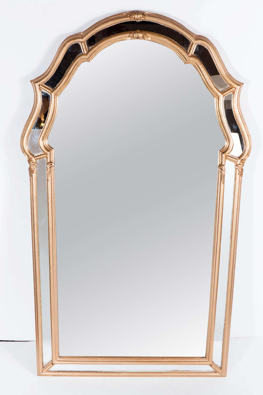 This stunning Mid-Century Modernist mirror has a gilt border with inset mirror panels with a scroll form detailing on the top. With its clean lines and luxurious finishes, this mirror would be a winning addition to practically any style of interior