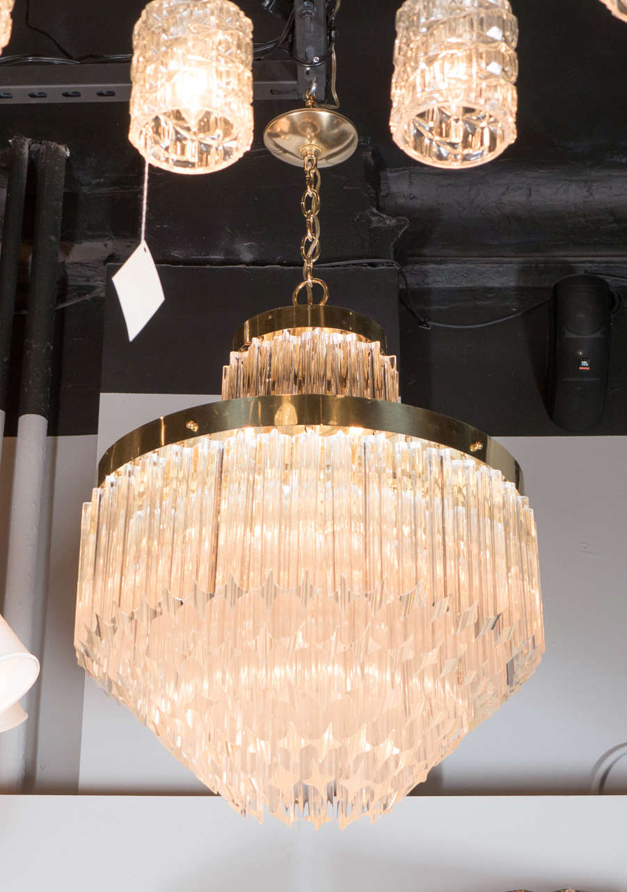 This exceptional Mid-Century Modernist Camer chandelier by Venini features individually handmade Murano glass triedre prisms hung in five tiers that have been cut at an angle, and individually hung from its brass frame. Each of the five tiers of