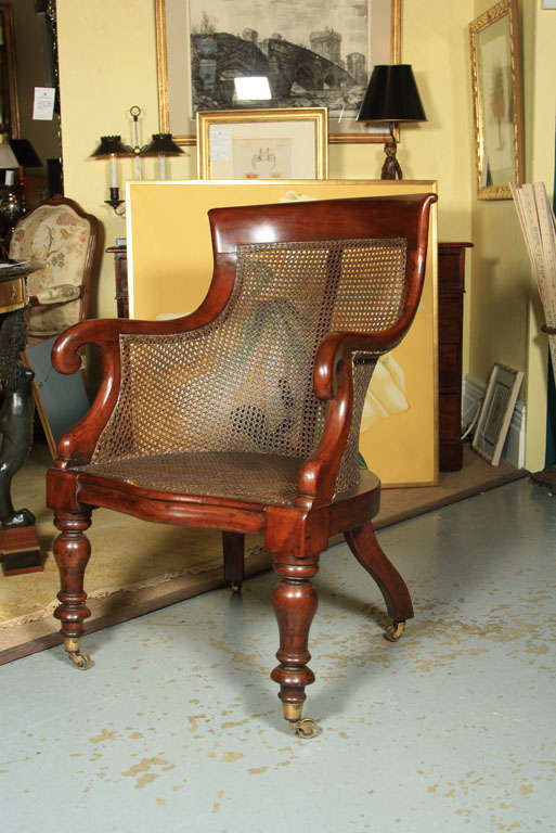 An English Regency mahogany & caned library chair on casters. Caning is new.