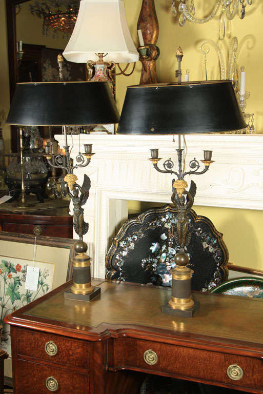 A pair of gilt and patinated French Empire style 2 arm candelabra with winged classical figures and tole shades.