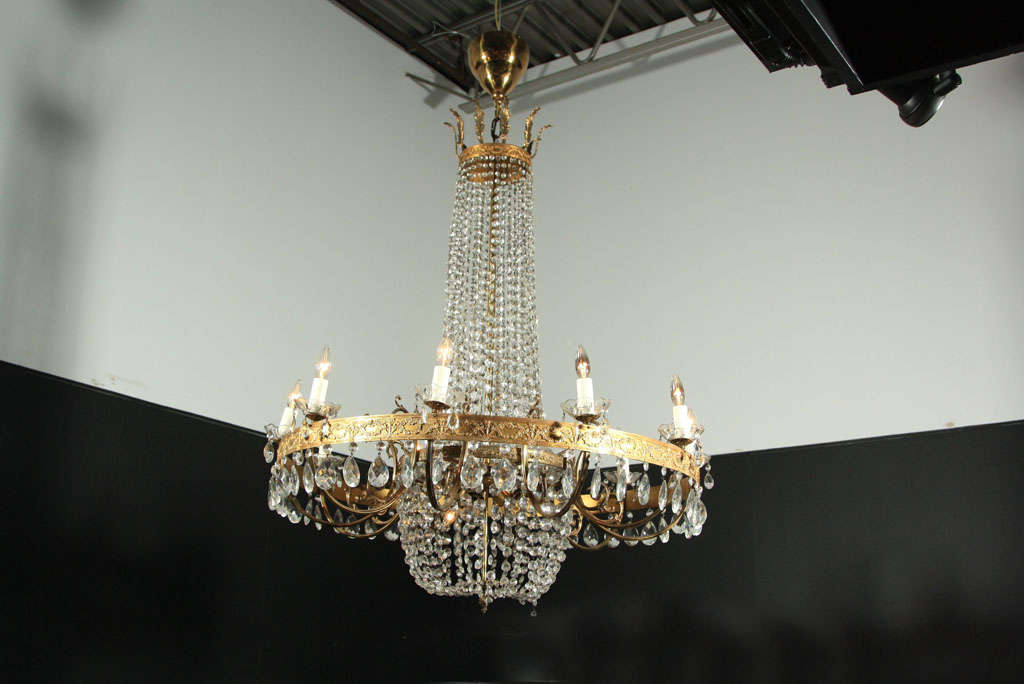 A pair of impressive 10 light Louis XVI style brass and beaded crystal chandeliers having a basket form lower section with three interior lights within a large molded brass ring.