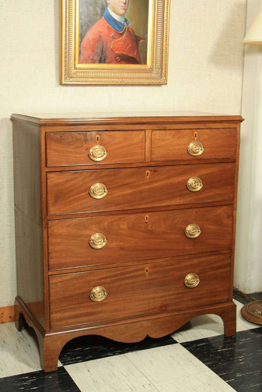 English mahogany chest of five drawers in two sections. Oval brass pulls, deeply scalloped apron and overall quality mahogany graining define this handsome chest.