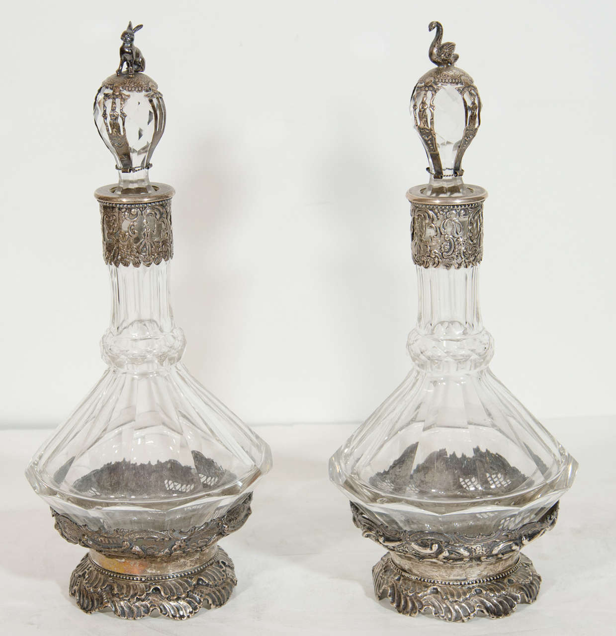 Pareja de decantadores octogonales de plata alemana antigua y cristal tallado con tapón. Cada jarra de cristal tallado, única en su género, está montada en filigrana de plata labrada a mano que representa escenas figuradas, y adornada además con