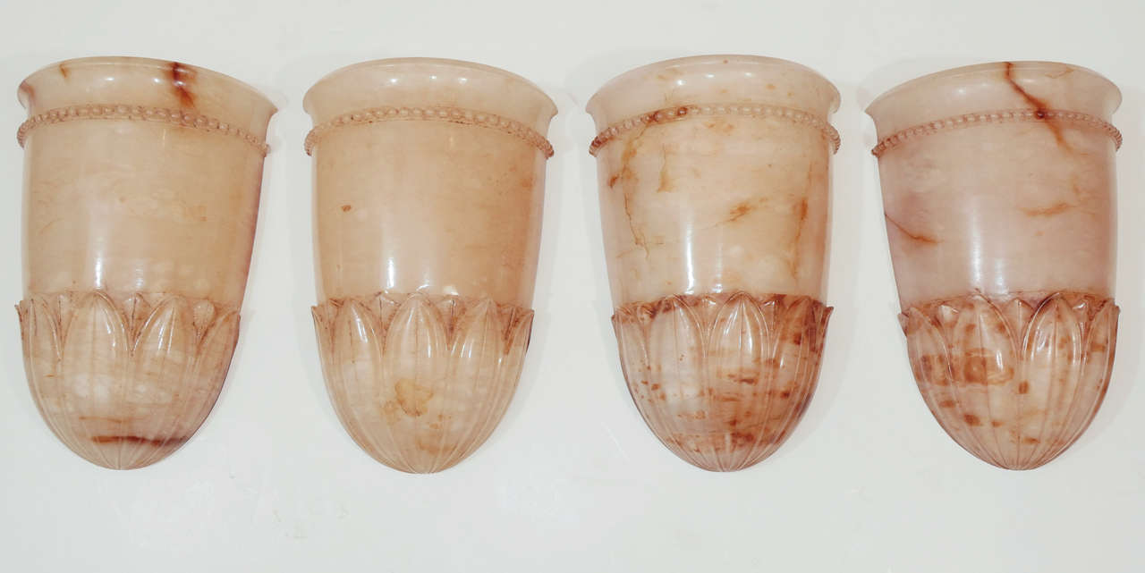 These urn shaped sconces, decorated with a base of acanthus leaves and trimmed with discrete beading are each carved from a single piece of a warm ivory alabaster, with terra cotta toned veining. May also be purchased in pairs.