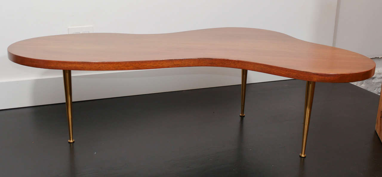 Medium sized  biomorphic coffee table by T.H. Robsjohn Gibbings on solid brass legs.